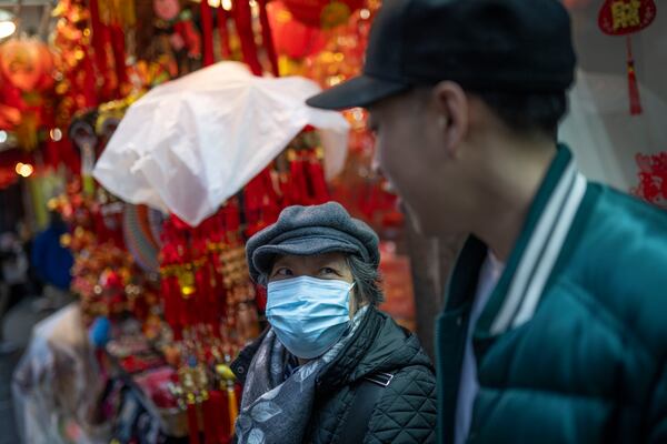 Karho Leung, 33, right, one of the founders of 12 Pell, a local barbershop, serendipitously happens upon his mother as she sits on a bench along Mott Street in Manhattan's Chinatown neighborhood, Thursday, Jan. 25, 2024, in New York. (AP Photo/John Minchillo)