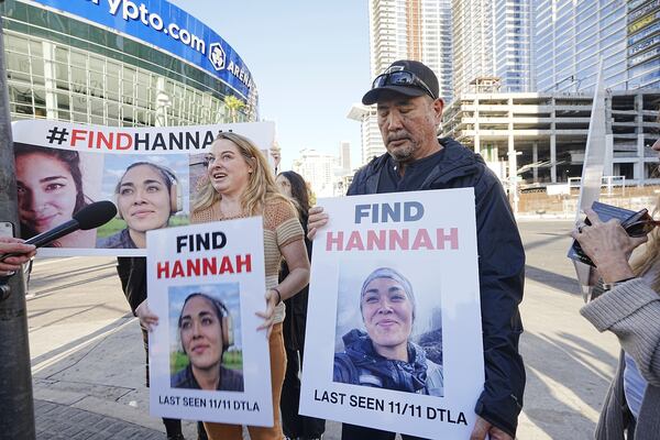 Ryan Kobayashi, right, holds a picture of his missing daughter Hannah Kobayashi outside Crypto.com Arena, Thursday, Nov. 21, 2024 in Los Angeles. (AP Photo/Damian Dovarganes)