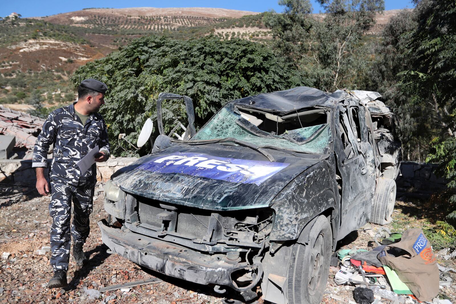 A policeman checks a destroyed journalists' car, at the site where an Israeli airstrike hit a compound housing journalists, killing three media staffers from two different news agencies according to Lebanon's state-run National News Agency, in Hasbaya village, southeast Lebanon, Friday, Oct. 25, 2024. (AP Photo/Mohammed Zaatari)