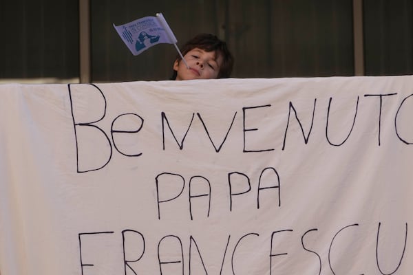 A child stands behind a banner reading, Welcome Pope Francis, in Ajaccio on the occasion of the Pontiff visit in the French island of Corsica, Sunday, Dec. 15, 2024. (AP Photo/Alessandra Tarantino)