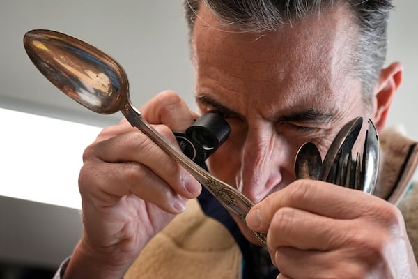 Associate appraiser Darrin Guitreau takes a close look at an inscription on the back of a silver spoon at Thomaston Place Auction Galleries, Tuesday, Nov. 19, 2024, in Thomaston, Maine. (AP Photo/Robert F. Bukaty)