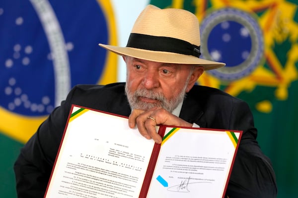 Brazil's President Luiz Inacio Lula da Silva holds up a bill that restricts the use of cell phones in schools nationwide, during a ceremony at the Planalto Palace, in Brasilia, Brazil, Monday, Jan. 13, 2025. (AP Photo/Eraldo Peres)