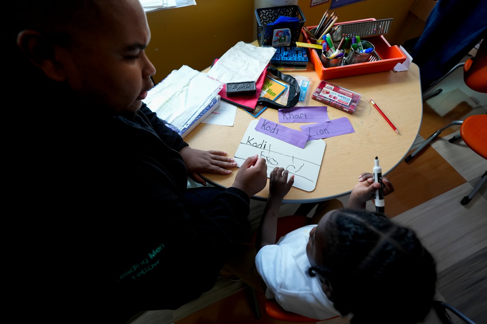 Leading Men fellow Davontez Johnson, left, helps preschooler Kodi to practice writing his name, Thursday, Oct. 3, 2024, at Dorothy I. Height Elementary School in Baltimore. (AP Photo/Stephanie Scarbrough)