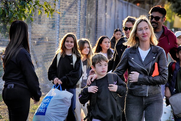 Palisades Charter Elementary School students and their parents arrive at their new school, the Brentwood Elementary Science Magnet school in the Brentwood section of Los Angeles on Wednesday, Jan. 15, 2025. (AP Photo/Richard Vogel)