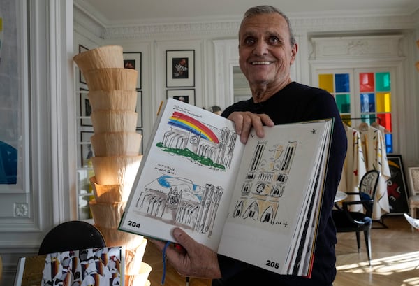 Designer Jean-Charles de Castelbajac displays his book with drawings of the Notre-Dame Cathedral during an interview with the Associated Press, Wednesday, Nov. 20, 2024 in Paris. (AP Photo/Michel Euler)