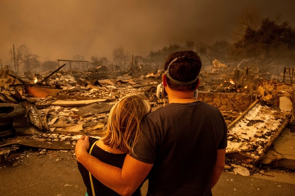 Megan Mantia, left, and her boyfriend Thomas, only first game given, return to Mantia's fire-damaged home after the Eaton Fire swept through, Wednesday, Jan. 8, 2025 in Altadena, Calif. (AP Photo/Ethan Swope)