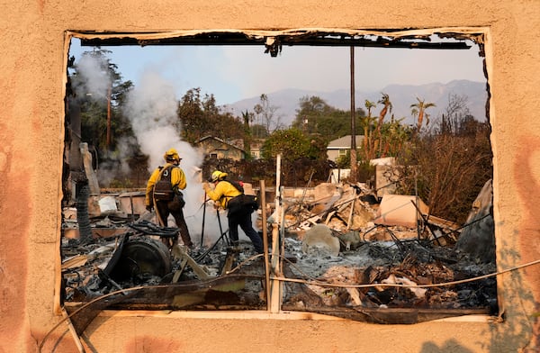 Firefighters extinguish burning embers at a house on Santa Rosa Avenue, also known as Christmas Tree Lane, Thursday, Jan. 9, 2025, in Altadena, Calif. (AP Photo/Chris Pizzello)