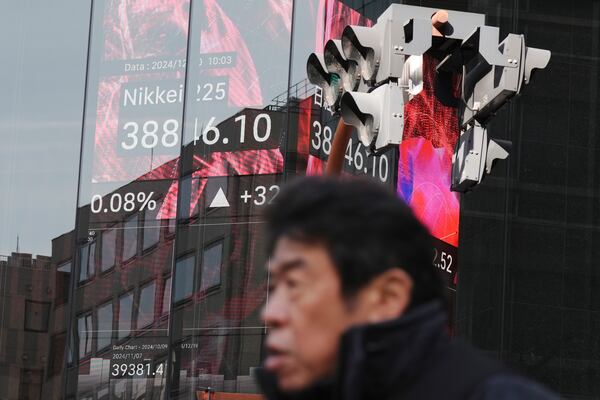 A person walks in front of an electronic stock board showing Japan's Nikkei index at a securities firm Friday, Dec. 20, 2024, in Tokyo. (AP Photo/Eugene Hoshiko)