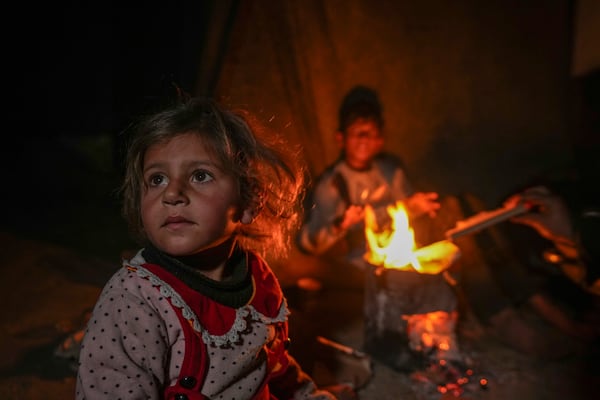 The grandchildren of Reda Abu Zarada sit by a fire at a camp by the sea in Khan Younis, Gaza Strip, Thursday, Dec. 19, 2024. (AP Photo/Abdel Kareem Hana)