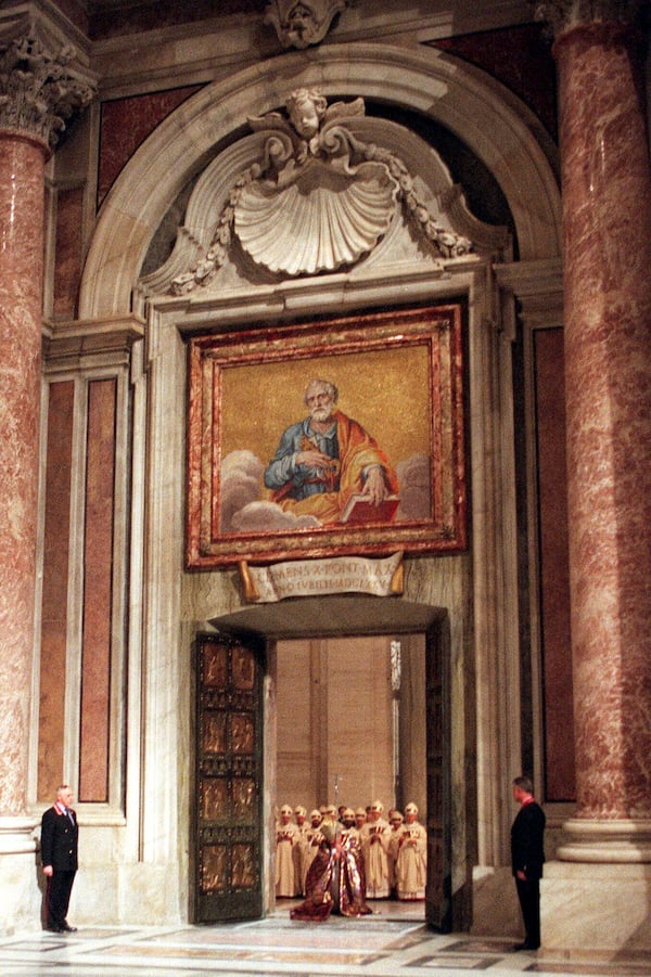 FILE - Pope John Paul II walks through the bronze Holy Door of St. Peter's Basilica at the Vatican, late Friday night, Dec. 24, 1999. (AP Photo/Andrew Medichini, File)