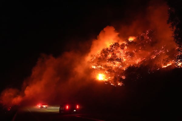 Vehicles pass through smoke from the Lilac Fire in Bonsall, Calif., Tuesday, Jan. 21, 2025. (AP Photo/Jae C. Hong)