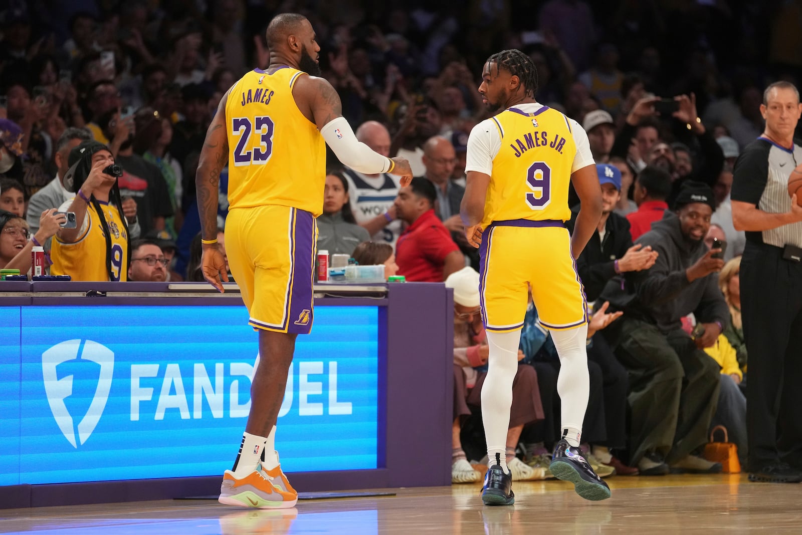 Los Angeles Lakers forward LeBron James (23) and guard Bronny James (9) stand on the court during the first half of an NBA basketball game against the Minnesota Timberwolves, Tuesday, Oct. 22, 2024, in Los Angeles. (AP Photo/Eric Thayer)