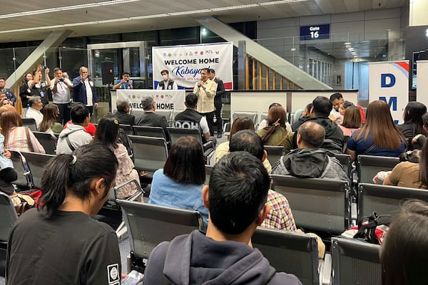 In this photo released by the Department of Migrant Workers, Secretary of Migrant Workers Hans Leo Cacdac, center, talks to freed Filipino crew-members, who were among those taken hostage aboard the Galaxy Leader in Yemen, as they arrive at Manila's International Airport on Thursday Jan. 23, 2025. (Department of Migrant Workers via AP)