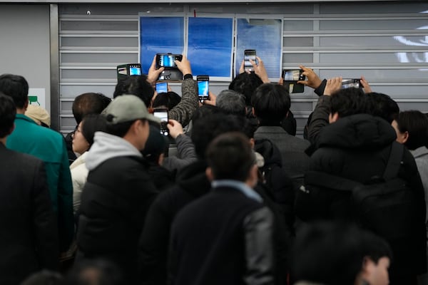 Relatives take photos of passenger lists at Muan International Airport in Muan, South Korea, Sunday, Dec. 29, 2024, after a passenger plane crashed at the airport. (AP Photo/Ahn Young-joon)