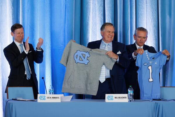 New North Carolina head football coach Bill Belichick, center, holds up a UNC branded sleeveless hoodie between North Carolina Chancellor Lee Roberts, left, and athletic director Bubba Cunningham, right, during an NCAA college football press conference in Chapel Hill, N.C., Thursday, Dec. 12, 2024. (AP Photo/Ben McKeown)