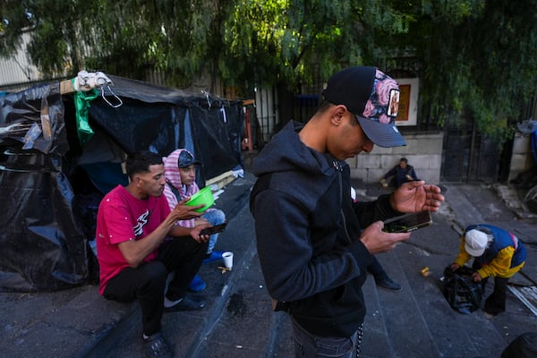 Yender Romero, from Venezuela, uses his cell phone to listen to news on the inauguration of U.S. President Donald Trump, at a migrant tent camp outside La Soledad church in Mexico City, Monday, Jan. 20, 2025. (AP Photo/Fernando Llano)