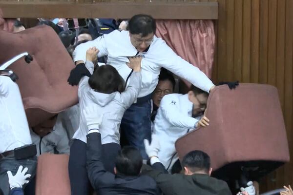 In this image made from video by Taiwan's EBC, lawmakers from the Democratic Progressive Party use chairs to block the entrance as members of the Nationalist Party, or Kuomintang, try to break into the Legislature in Taipei, Taiwan on Friday, Dec 20, 2024. (EBC via AP )