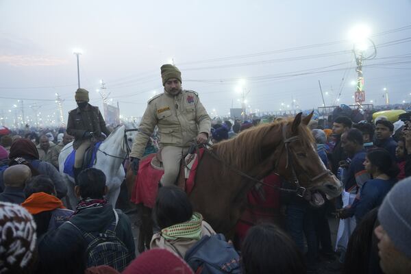 Policemen control the crowd as Hindu devotees gather to take a holy dip by the banks of the Sangam, the confluence of the Ganges, the Yamuna and the mythical Saraswati rivers, on "Mauni Amavasya" or new moon day during the Maha Kumbh festival in Prayagraj, Uttar Pradesh, India, Wednesday, Jan. 29, 2025. (AP Photo/Deepak Sharma)