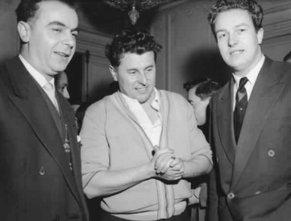 FILE - Pierre Poujade, center, whose newly formed anti-tax party has surprised the world by winning at least 50 seats in the French elections, with Andre Gayard, left, and Jean-Marie Le Pen, right, chats with two members of this party who have been elected to parliament, at his headquarters in Ablon, near Paris, France on Jan. 3, 1956. (AP Photo/H. Babout, File)