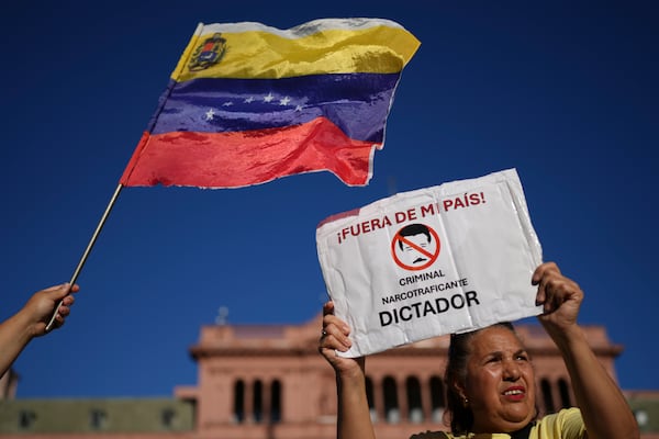 An opponent of Venezuelan President Nicolas Maduro holds a banner that reads in Spanish, "Out of my country! Criminal, narco-trafficker, dictator" at a demonstration at the Plaza de Mayo the day before Maduro's inauguration for a third term, in Buenos Aires, Argentina, Thursday, Jan. 9, 2025. (AP Photo/Natacha Pisarenko)