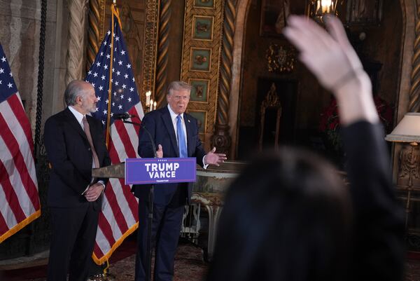 President-elect Donald Trump speaks at a news conference at Mar-a-Lago, Monday, Dec. 16, 2024, in Palm Beach, Fla., as Commerce Secretary nominee Howard Lutnick listens. (AP Photo/Evan Vucci)