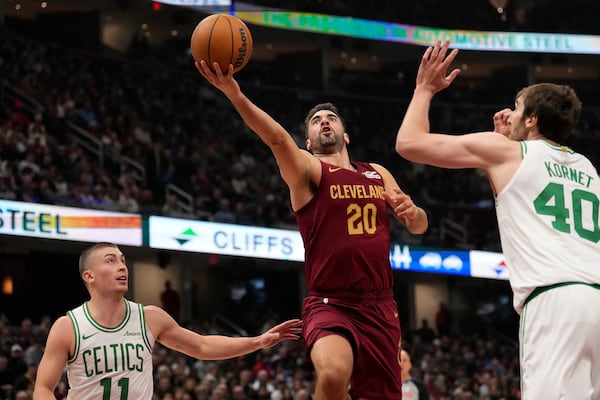 Cleveland Cavaliers forward Georges Niang (20) goes to the basket between Boston Celtics guard Payton Pritchard (11) and center Luke Kornet (40) in the first half of an NBA basketball game, Sunday, Dec. 1, 2024, in Cleveland. (AP Photo/Sue Ogrocki)