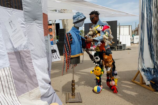 A designer sets up his upcycle outfit on a mannequin during a thrift and an upcycle show in Accra, Ghana, Sunday, Oct. 27, 2024. (AP Photo/Misper Apawu)