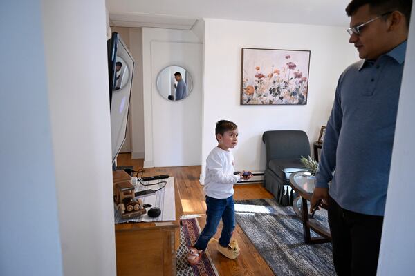 In this Jan. 3, 2025 photo, Jesus Lopez, left, asks his father Rogers Lopez, right, to watch television with him in their apartment in New Milford, Conn. (AP Photo/Jessica Hill)