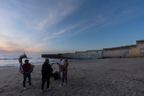 A band serenades two women near where the border wall separating Mexico and the United States reaches the Pacific Ocean Monday, Jan. 20, 2025, in Tijuana, Mexico. (AP Photo/Gregory Bull)