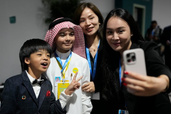 Huang Jiangcheng, from China, left, and Fareed Mohammed Felemban, from Saudi Arabia, pose for photos after speaking at a youth session during the COP29 U.N. Climate Summit, Monday, Nov. 18, 2024, in Baku, Azerbaijan. (AP Photo/Rafiq Maqbool)