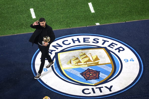 Manchester City's Rodri waves to fans with his Ballon d'Or Golden Ball trophy ahead of the British Premier League soccer match between Manchester City and Tottenham Hotspur, at the Etihad Stadium, Manchester, England, Saturday Nov. 23, 2024. (Carl Recine, Pool Photo via AP)