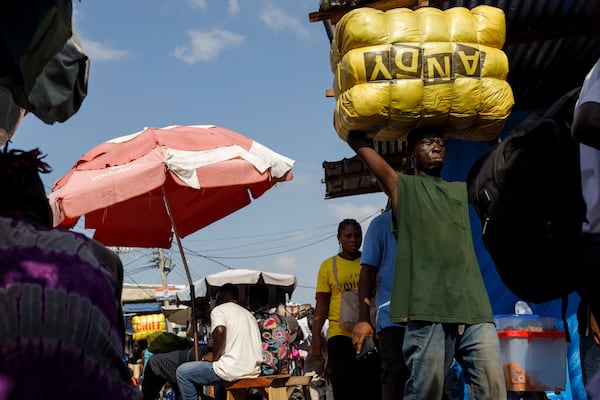 A head porter carries a bale of Second-hand clothes at Kantamanto market, one of the world's largest second-hand clothes markets in Accra, Ghana, Thursday, Oct. 31, 2024. (AP Photo/Misper Apawu)