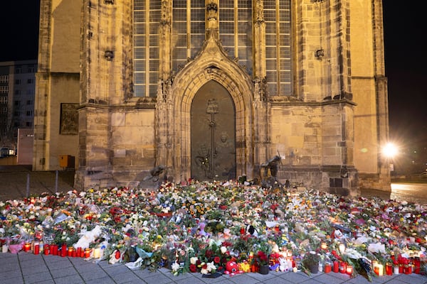 Candles, flowers and wreaths sit in front of the entrance to St. John's Church early Sunday, Dec. 22, 2024, in Magdeburg, Germany, after a car drove into a crowd at a Christmas market on Friday, Dec. 20. (Sebastian Kahnert/dpa via AP)