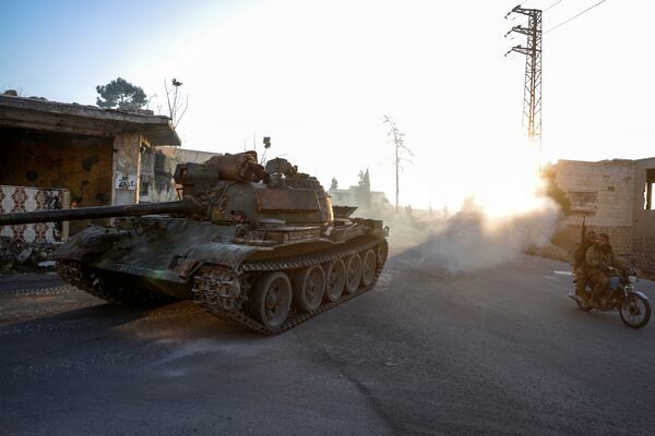 Syrian opposition fighters drive a motorcycle and an armoured vehicle seized from the Syrian army in the town of Maarat al-Numan, south of Idlib, Syria, Tuesday Dec. 3, 2024.(AP Photo/Omar Albam)