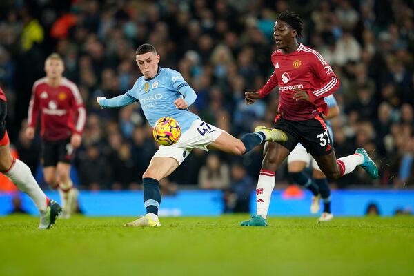 Manchester City's Phil Foden kicks the ball ahead of Manchester United's Kobbie Mainoo during the English Premier League soccer match between Manchester City and Manchester United at the Etihad Stadium in Manchester, Sunday, Dec. 15, 2024. (AP Photo/Dave Thompson)