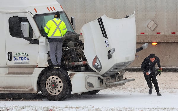 Truckers fight the weather as they stop on Interstate 44 in Fenton, Mo. to change wiper blades as sleet falls on Sunday, Jan. 5, 2025. (Cohen/St. Louis Post-Dispatch via AP)