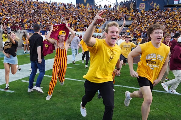 Arizona State fans run on the field following a 28-23 win over BYU in an NCAA college football game Saturday, Nov. 23, 2024, in Tempe, Ariz.