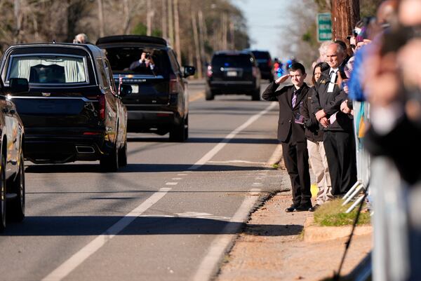 A young boy salutes as the hearse carrying the flag-draped casket of former President Jimmy Carter moves through downtown Plains, Ga., Saturday, Jan. 4, 2025. (AP Photo/Mike Stewart)