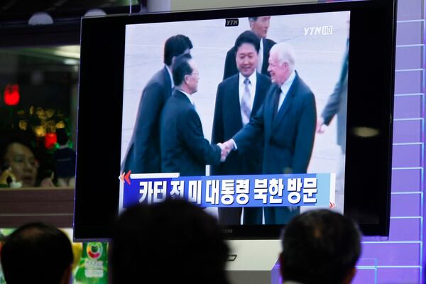 FILE - South Koreans watch a TV news program showing former President Jimmy Carter arriving in Pyongyang, North Korea, at the Seoul Railway Station in Seoul, South Korea, Aug. 25, 2010. Carter arrived in the capital of communist North Korea on a private, humanitarian mission to bring home an American sentenced to eight years' hard labor for trespassing. The Korean letters on the screen read: "Visit of former U.S. President Jimmy Carter in North Korea." (AP Photo/Ahn Young-joon, File)